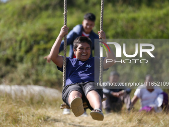 A Nepali boy gestures as he plays on a swing installed on a hillside surrounding Kathmandu Valley with the arrival of the fortnightly festiv...