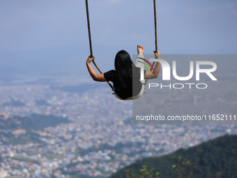 A Nepali woman plays on a swing installed on a hillside surrounding Kathmandu Valley with the arrival of the fortnightly festival of Dashain...