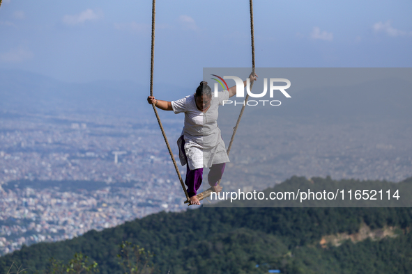 A Nepali woman plays on a swing installed on a hillside surrounding Kathmandu Valley with the arrival of the fortnightly festival of Dashain...