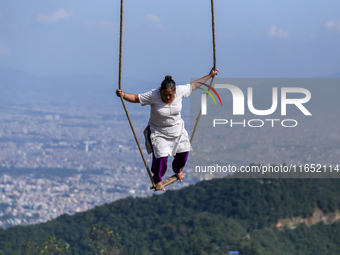 A Nepali woman plays on a swing installed on a hillside surrounding Kathmandu Valley with the arrival of the fortnightly festival of Dashain...