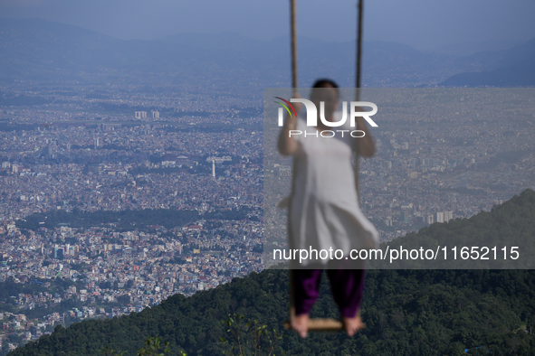 A Nepali woman plays on a swing installed on a hillside surrounding Kathmandu Valley with the arrival of the fortnightly festival of Dashain...