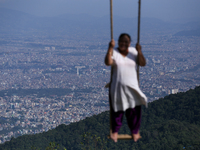 A Nepali woman plays on a swing installed on a hillside surrounding Kathmandu Valley with the arrival of the fortnightly festival of Dashain...