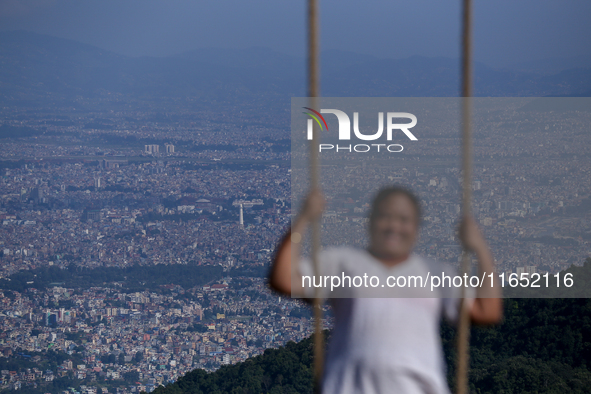 A Nepali woman plays on a swing installed on a hillside surrounding Kathmandu Valley with the arrival of the fortnightly festival of Dashain...