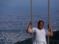 A Nepali woman plays on a swing installed on a hillside surrounding Kathmandu Valley with the arrival of the fortnightly festival of Dashain...