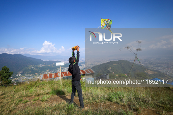 A Nepali boy flies a kite from a hilltop surrounding Kathmandu Valley with the arrival of the fortnightly festival of Dashain, on October 9,...