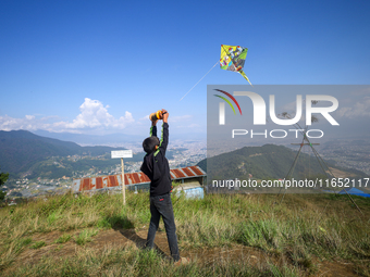 A Nepali boy flies a kite from a hilltop surrounding Kathmandu Valley with the arrival of the fortnightly festival of Dashain, on October 9,...