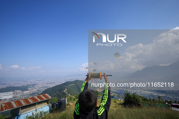 A Nepali boy flies a kite from a hilltop surrounding Kathmandu Valley with the arrival of the fortnightly festival of Dashain, on October 9,...