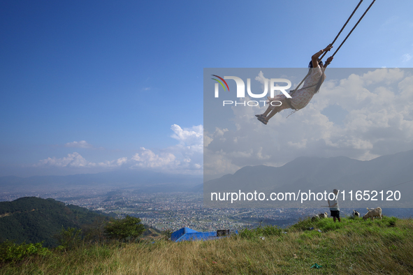 A Nepali woman plays on a swing installed on a hillside surrounding Kathmandu Valley with the arrival of the fortnightly festival of Dashain...