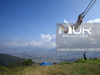 A Nepali woman plays on a swing installed on a hillside surrounding Kathmandu Valley with the arrival of the fortnightly festival of Dashain...