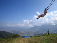 A Nepali woman plays on a swing installed on a hillside surrounding Kathmandu Valley with the arrival of the fortnightly festival of Dashain...