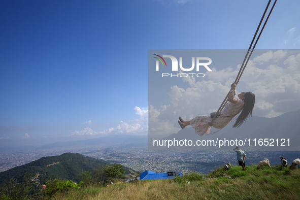 A Nepali woman plays on a swing installed on a hillside surrounding Kathmandu Valley with the arrival of the fortnightly festival of Dashain...