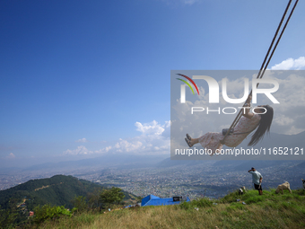 A Nepali woman plays on a swing installed on a hillside surrounding Kathmandu Valley with the arrival of the fortnightly festival of Dashain...