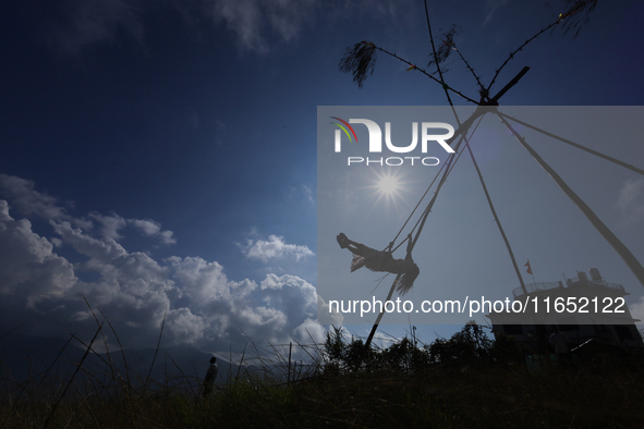 A Nepali woman is silhouetted against the sun as she plays on a swing installed on a hillside surrounding Kathmandu Valley with the arrival...