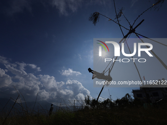 A Nepali woman is silhouetted against the sun as she plays on a swing installed on a hillside surrounding Kathmandu Valley with the arrival...