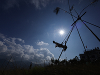 A Nepali woman is silhouetted against the sun as she plays on a swing installed on a hillside surrounding Kathmandu Valley with the arrival...