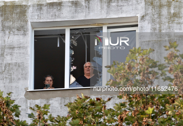 People look out of a broken window of the residential building damaged by a Russian drone attack in Chornomorsk, Odesa region, southern Ukra...