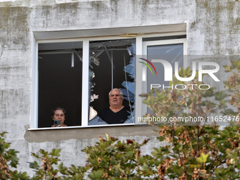 People look out of a broken window of the residential building damaged by a Russian drone attack in Chornomorsk, Odesa region, southern Ukra...