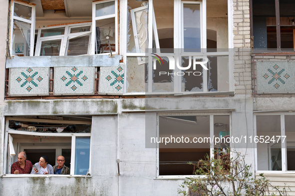 People stand on the balcony of a residential building damaged by a Russian drone attack in Chornomorsk, Odesa region, southern Ukraine, on O...