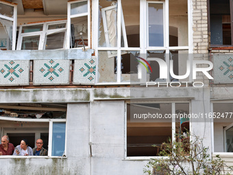 People stand on the balcony of a residential building damaged by a Russian drone attack in Chornomorsk, Odesa region, southern Ukraine, on O...