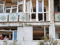 People stand on the balcony of a residential building damaged by a Russian drone attack in Chornomorsk, Odesa region, southern Ukraine, on O...