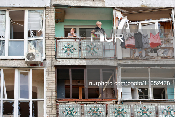 People stand on the balcony of a residential building damaged by a Russian drone attack in Chornomorsk, Odesa region, southern Ukraine, on O...