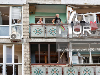 People stand on the balcony of a residential building damaged by a Russian drone attack in Chornomorsk, Odesa region, southern Ukraine, on O...