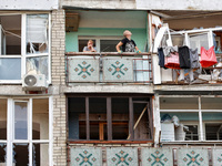 People stand on the balcony of a residential building damaged by a Russian drone attack in Chornomorsk, Odesa region, southern Ukraine, on O...