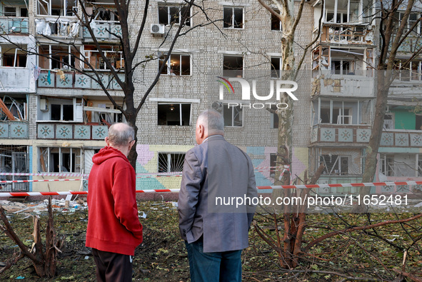 People stand outside a residential building damaged by a Russian drone attack in Chornomorsk, Odesa region, southern Ukraine, on October 9,...