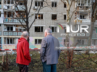 People stand outside a residential building damaged by a Russian drone attack in Chornomorsk, Odesa region, southern Ukraine, on October 9,...