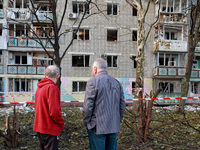 People stand outside a residential building damaged by a Russian drone attack in Chornomorsk, Odesa region, southern Ukraine, on October 9,...