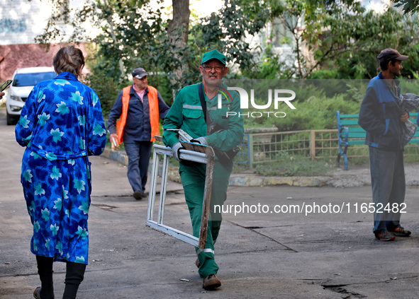 City crew work outside a residential building damaged by a Russian drone attack in Chornomorsk, Odesa region, southern Ukraine, on October 9...