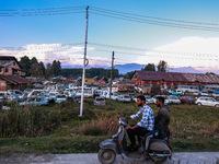 Kashmiri boys ride a scooter as seized and damaged vehicles are seen inside a yard on the outskirts of Srinagar, Jammu and Kashmir, India, o...