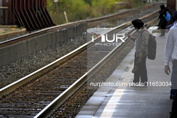 A commuter looks at his phone while waiting for a train at the Innovation District station in downtown Brampton, Ontario, Canada, on October...