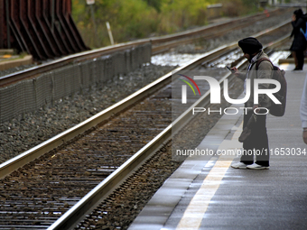 A commuter looks at his phone while waiting for a train at the Innovation District station in downtown Brampton, Ontario, Canada, on October...