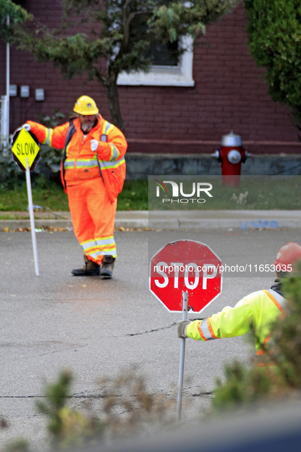 Crew members hold traffic signs at a construction site in downtown Brampton, Ontario, Canada, on October 9, 2024. 