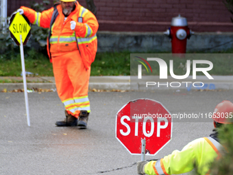 Crew members hold traffic signs at a construction site in downtown Brampton, Ontario, Canada, on October 9, 2024. (