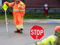 Crew members hold traffic signs at a construction site in downtown Brampton, Ontario, Canada, on October 9, 2024. (