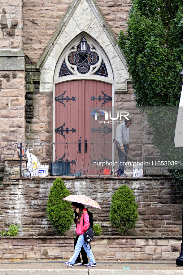 A person works on the steps of St. Paul's United Church as pedestrians walk along Main Street in downtown Brampton, Ontario, Canada, on Octo...