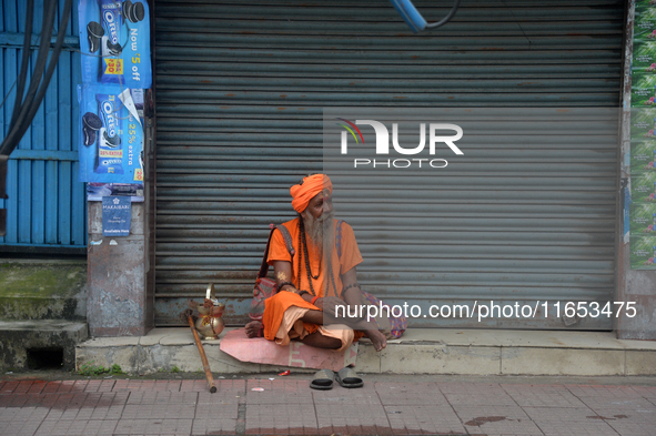 A Sadhu (Hindu Holy Man) sits in front of the shuttered shops as he begs for alms in Siliguri, India, on October 10, 2024. 