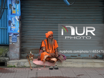 A Sadhu (Hindu Holy Man) sits in front of the shuttered shops as he begs for alms in Siliguri, India, on October 10, 2024. (