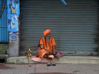 A Sadhu (Hindu Holy Man) sits in front of the shuttered shops as he begs for alms in Siliguri, India, on October 10, 2024. (