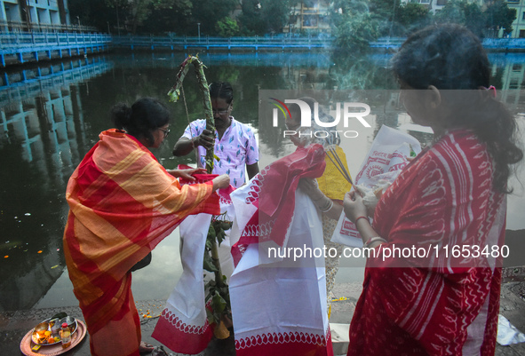 Hindu devotees perform prayers in front of a banana tree trunk as part of a ritual Nabapatrika on the banks of the Ganges River during the D...