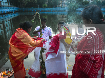 Hindu devotees perform prayers in front of a banana tree trunk as part of a ritual Nabapatrika on the banks of the Ganges River during the D...