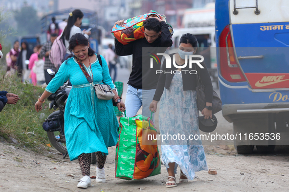 People carry their bags and luggage as they prepare to return to their permanent homes from Kathmandu, Nepal, on October 10, 2024, to celebr...