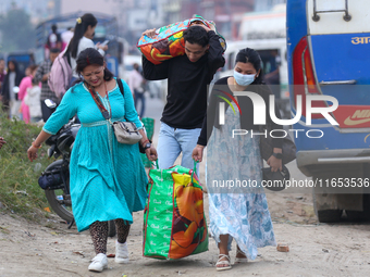 People carry their bags and luggage as they prepare to return to their permanent homes from Kathmandu, Nepal, on October 10, 2024, to celebr...