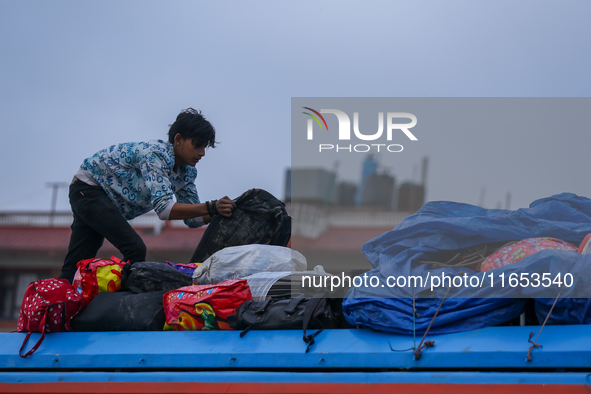 The staff of a passenger vehicle arranges luggage on top of the vehicle as it prepares to depart from Kathmandu, Nepal, on October 10, 2024....