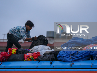 The staff of a passenger vehicle arranges luggage on top of the vehicle as it prepares to depart from Kathmandu, Nepal, on October 10, 2024....