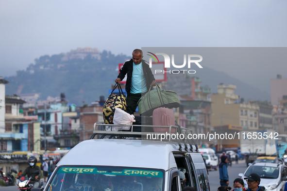 The staff of a passenger bus arranges luggage on top of the vehicle as it prepares to depart from Kathmandu, Nepal, on October 10, 2024. Tho...