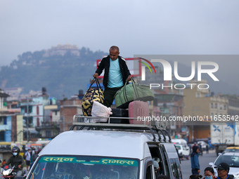 The staff of a passenger bus arranges luggage on top of the vehicle as it prepares to depart from Kathmandu, Nepal, on October 10, 2024. Tho...