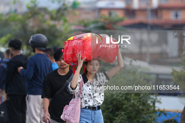 People carry their bags and luggage as they prepare to return to their permanent homes from Kathmandu, Nepal, on October 10, 2024, to celebr...